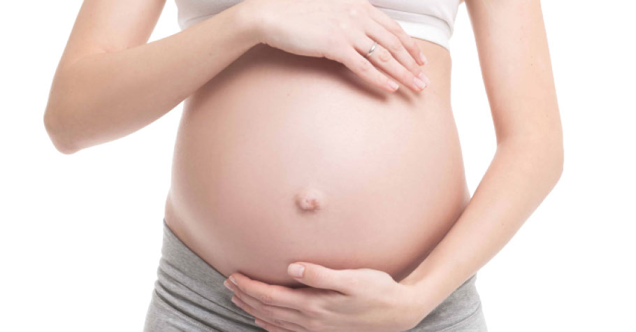 Un vientre embarazado acunado por manos femeninas