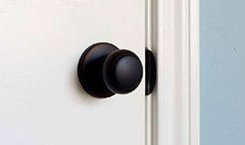 A dark metal doorknob on a white door