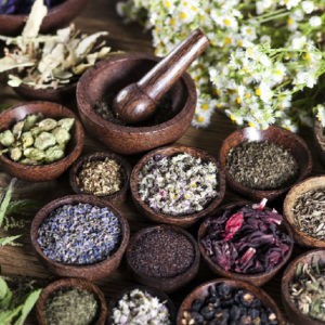 Collection of herbs in wooden bowls with mortar and pestle