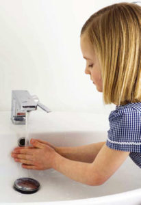 Chica lavándose las manos en el fregadero blanco