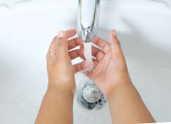 Hands being held under water faucet