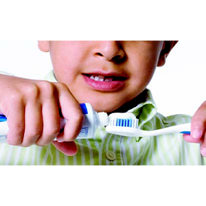 Child applying toothpaste onto toothbrush